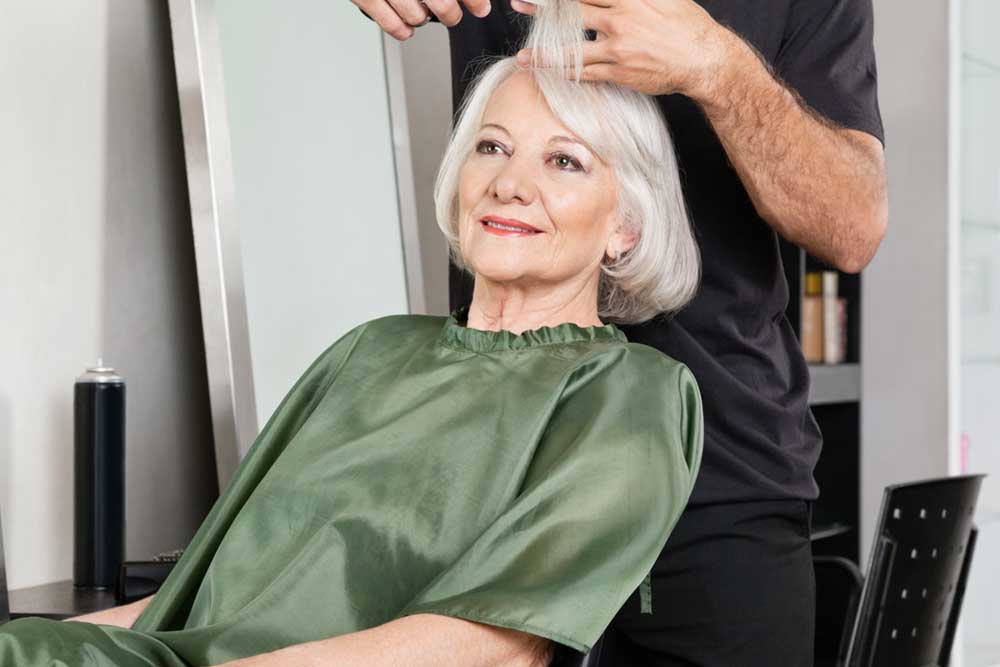 Senior woman having hair cut at beauty salon