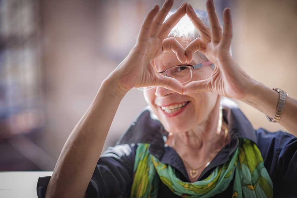 Cute senior woman making a heart shape with her hands and fingers