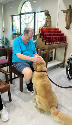 A resident sitting with a therapy dog in the chapel at Saints Joachim & Anne