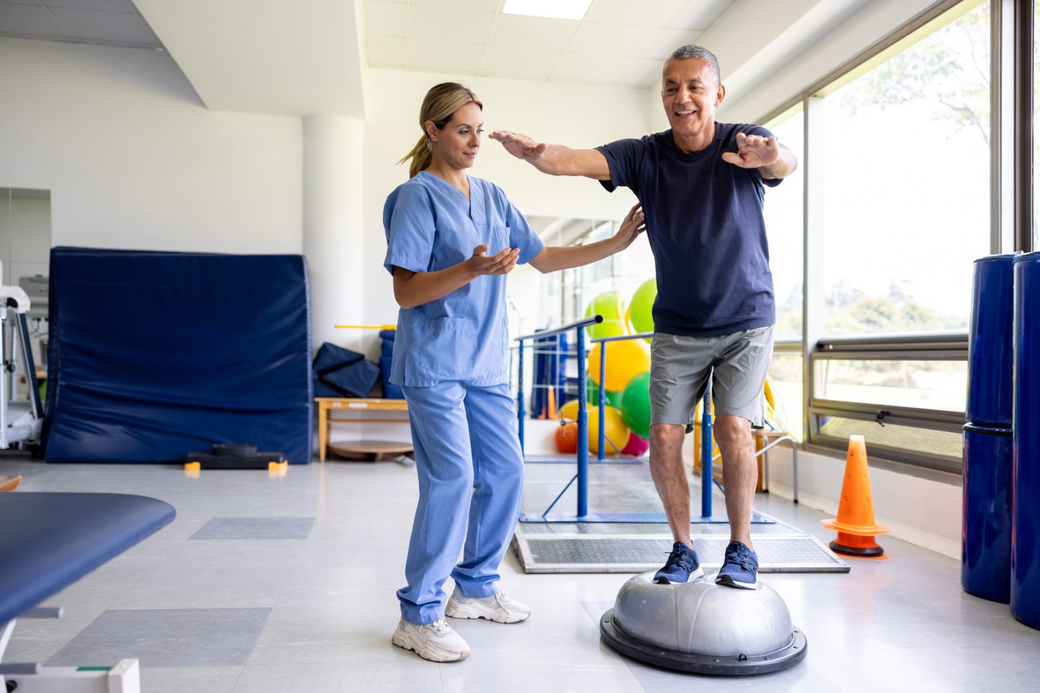 A physical therapist guides a patient through a balance exercise on a stability trainer